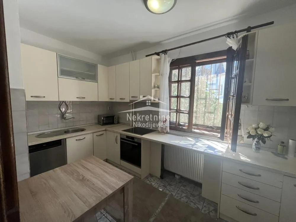 Small kitchen with white cabinets, stove, and a window.