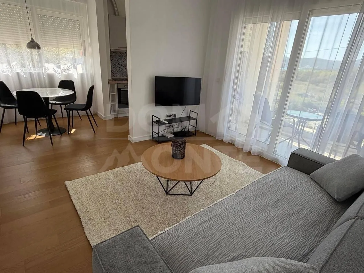 Living room with a sofa, coffee table, and dining area in the background.