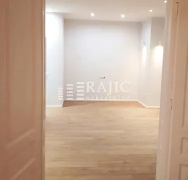 Empty room with laminate flooring and recessed lighting viewed through a doorway. - image 3