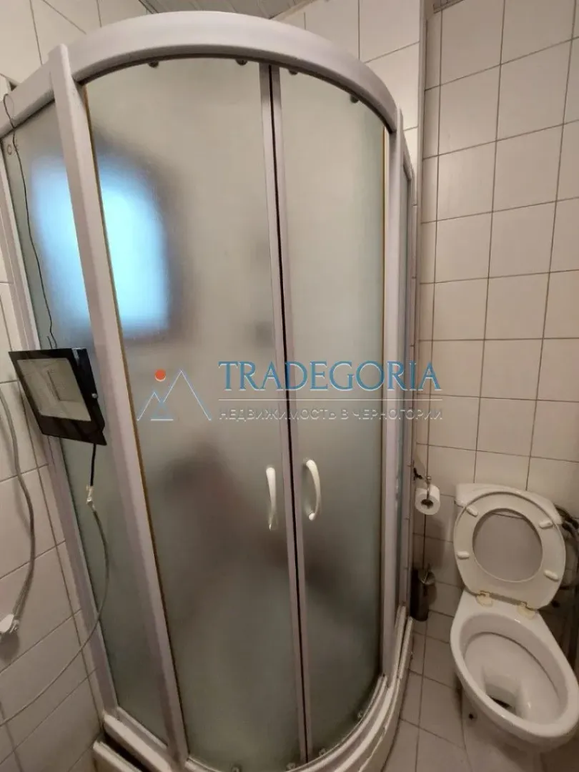 Kupatilo sa tuš kabinom i toaletom obloženo keramičkim pločicama.