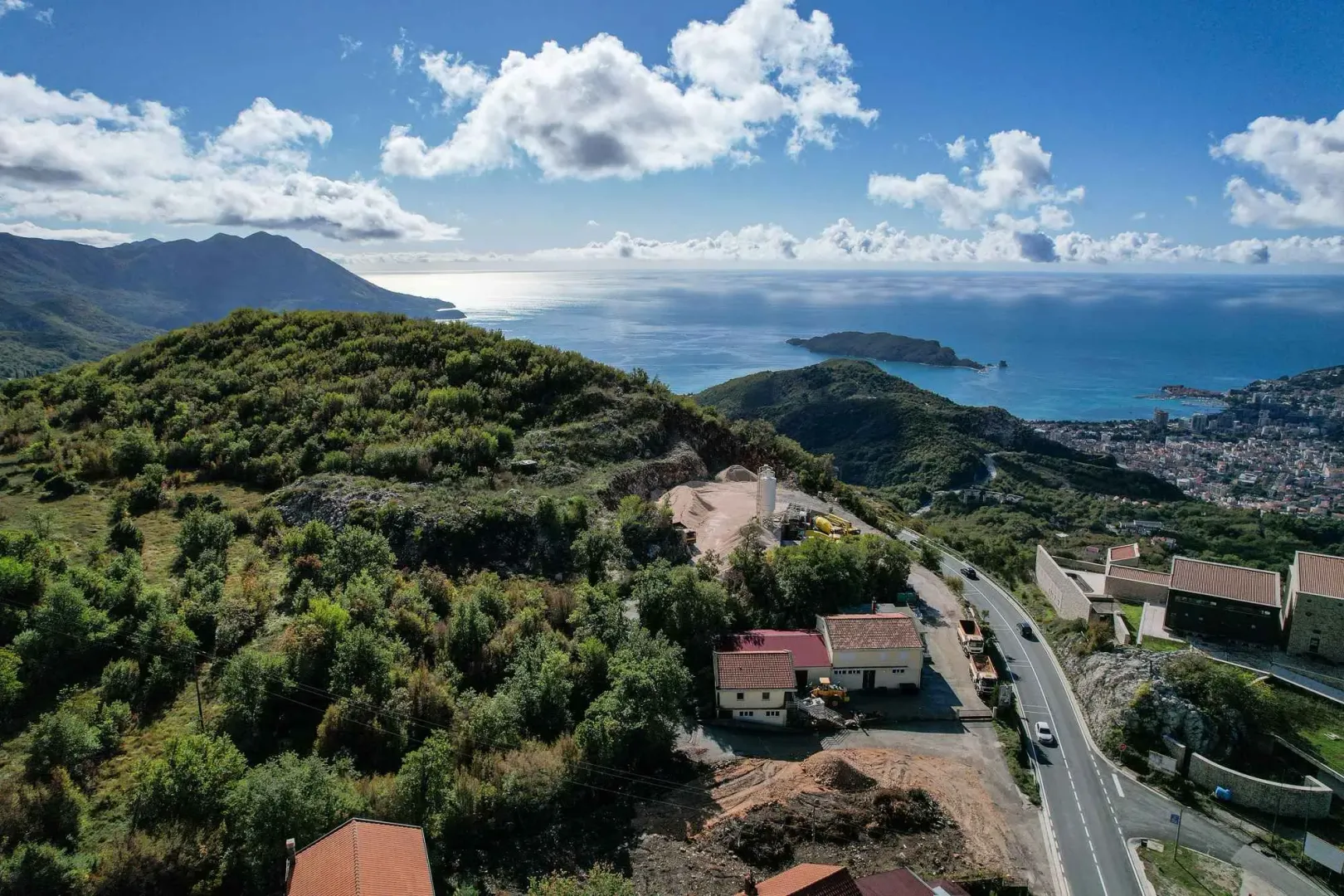 Pogled iz vazduha na brdoviti pejzaž, obalu i more sa ostrvom u daljini.