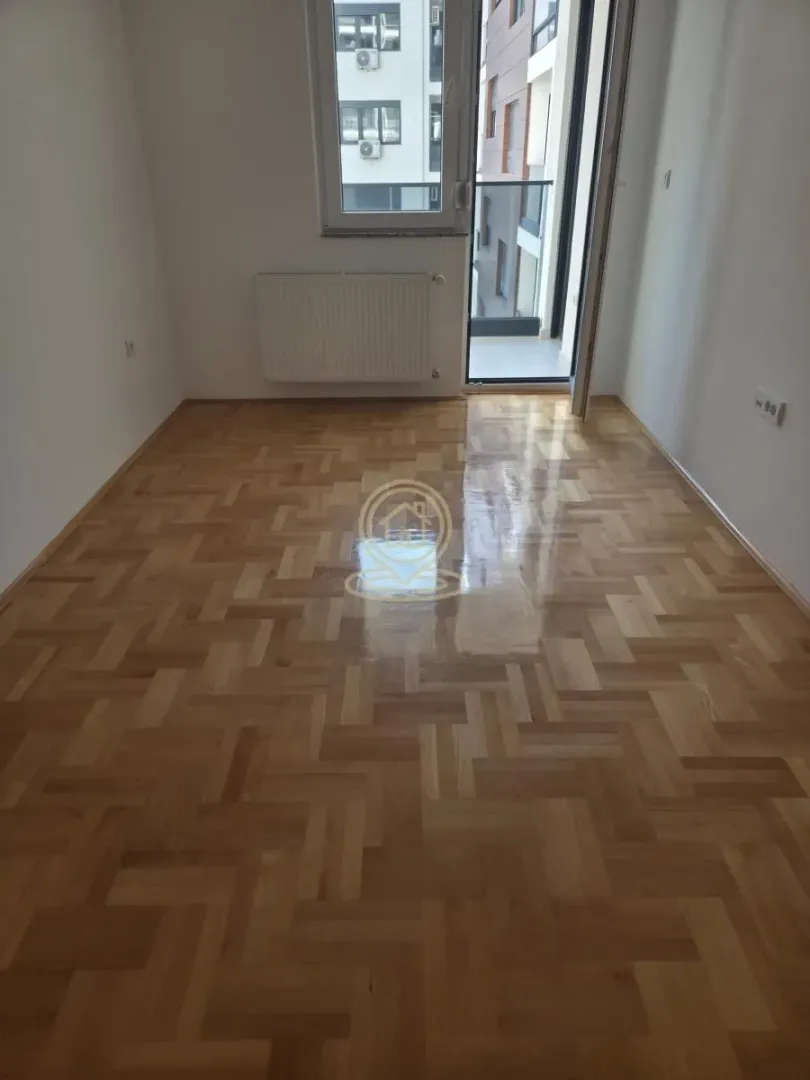 Prazna soba sa parketom i izlazom na terasu.