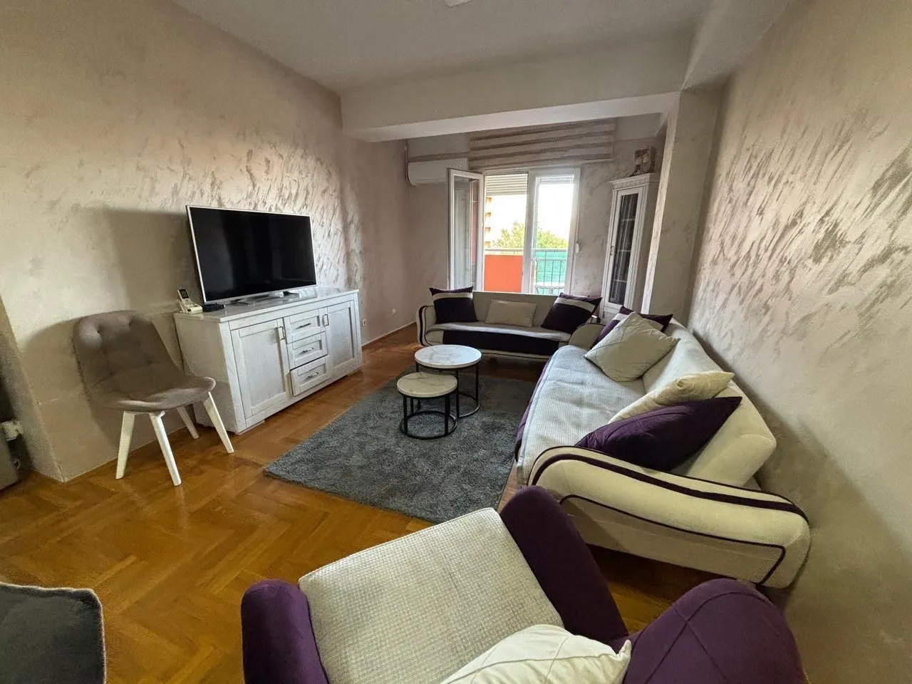 Dnevna soba sa garniturom, televizorom i izlazom na terasu.