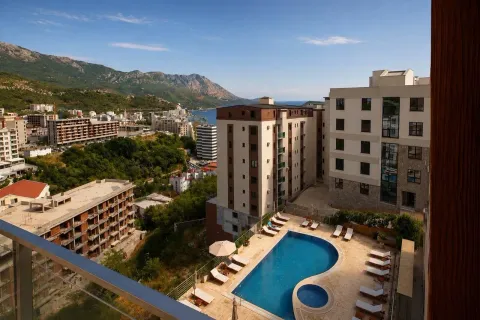 View from the terrace overlooking the pool and surrounding buildings with mountains in the background. - image 6