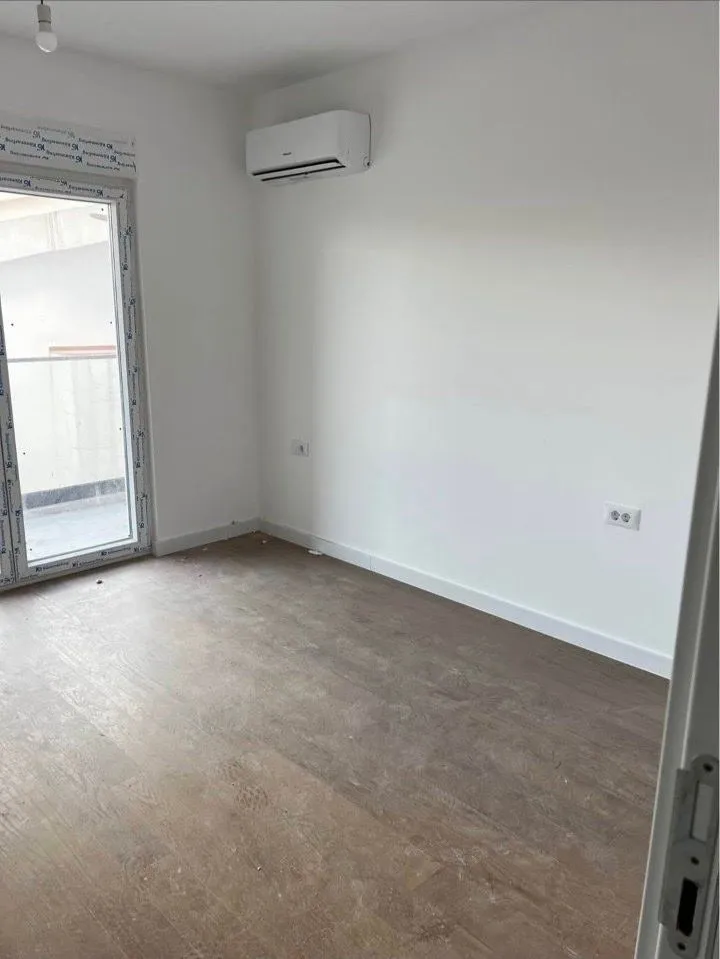 Empty room with laminate flooring, air conditioner, and balcony access.