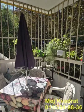 Natkrivena terasa opremljena baštenskim stolom, stolicama i suncobranom. - image 3