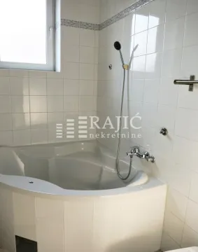 Small bathroom with a corner bathtub and white wall tiles. - image 5