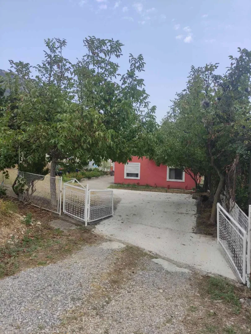 Dvorište porodične kuće sa kapijom i zelenilom.