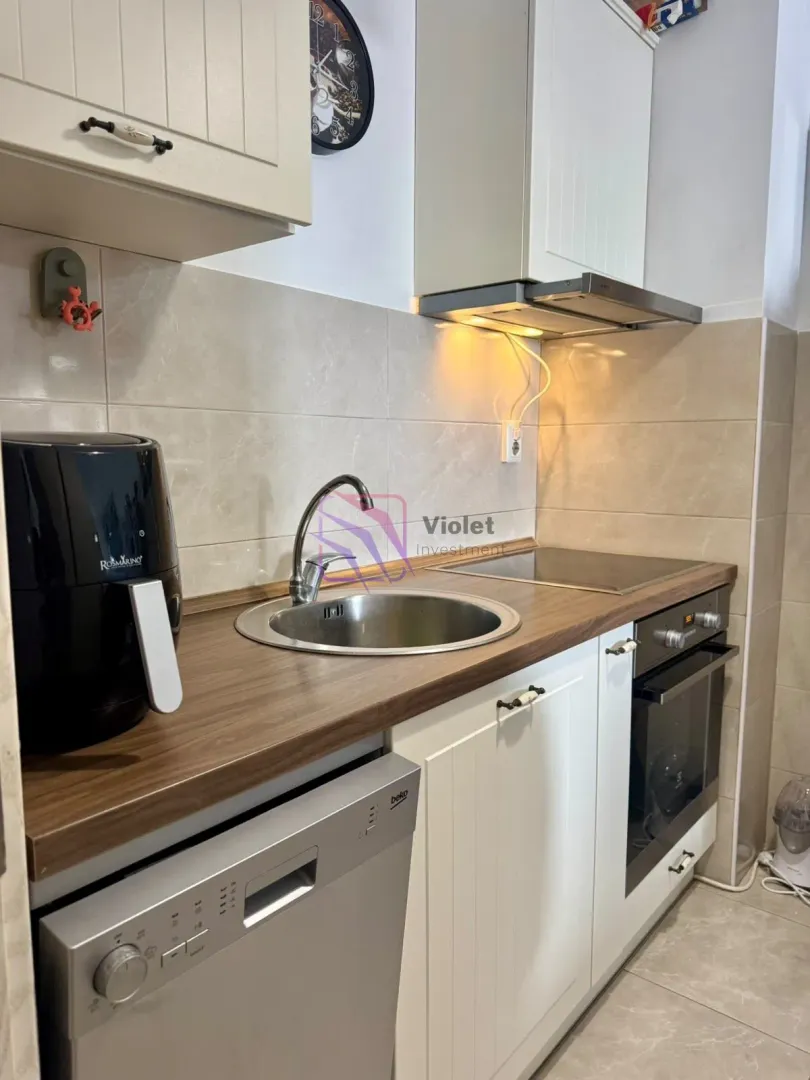 Compact kitchen with a sink, oven, and built-in cabinetry.