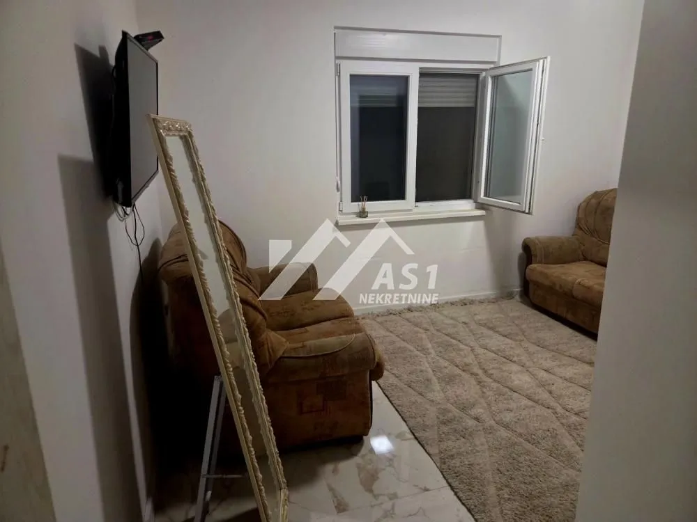 Small living room with seating furniture, television, and a window.