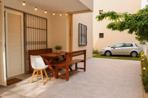 Natkrivena terasa sa drvenim stolom i klupama ispred ulaza u kuću. - image 6