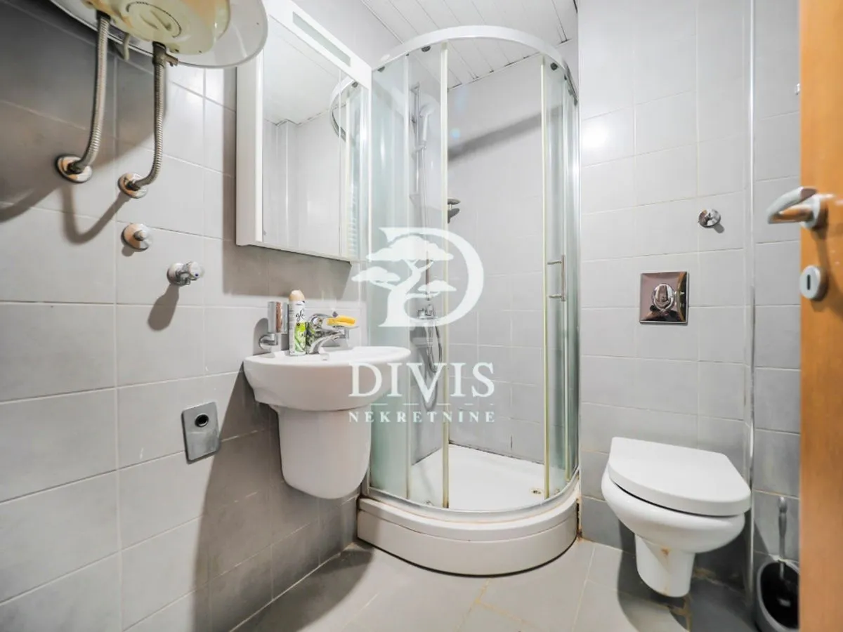 Smaller bathroom with a shower cabin, washbasin, and toilet.