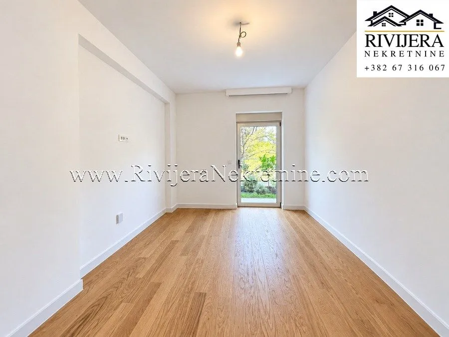 Empty room with white walls, wooden parquet flooring, and access to the terrace.