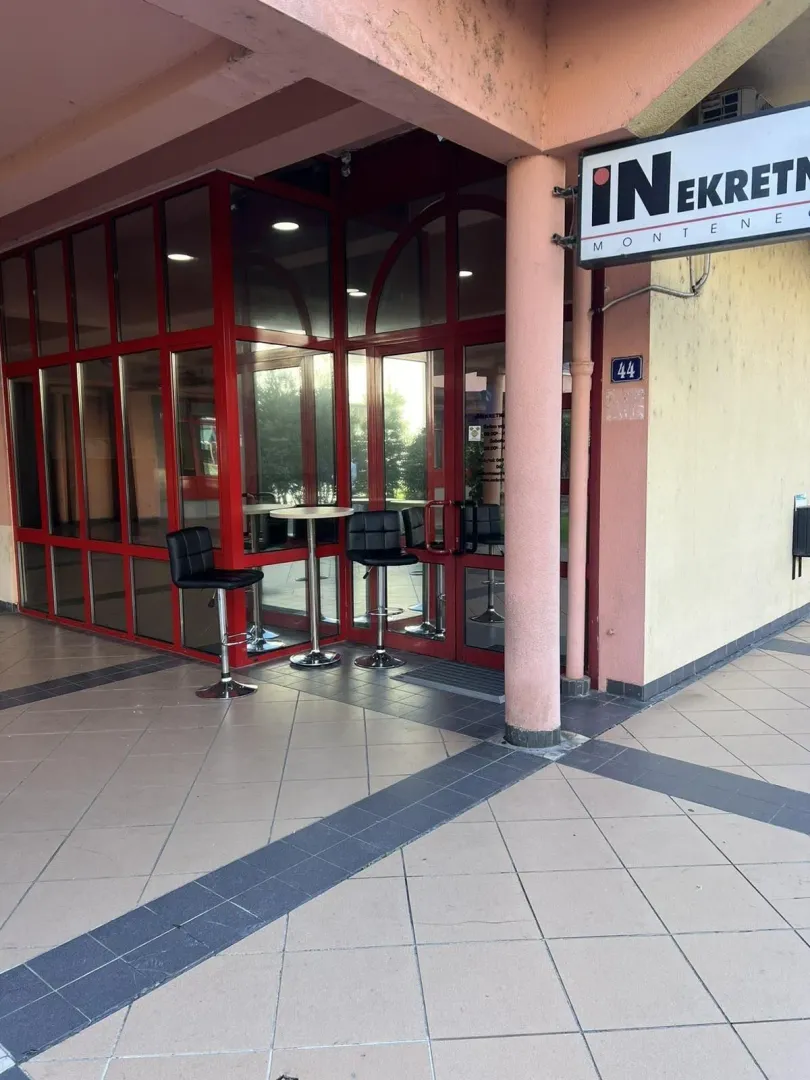Entrance to a commercial space with a glass facade and red frames.