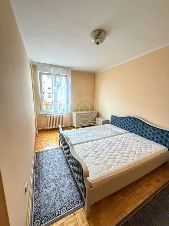 Spavaća soba sa bračnim krevetom, parketom i prozorom.