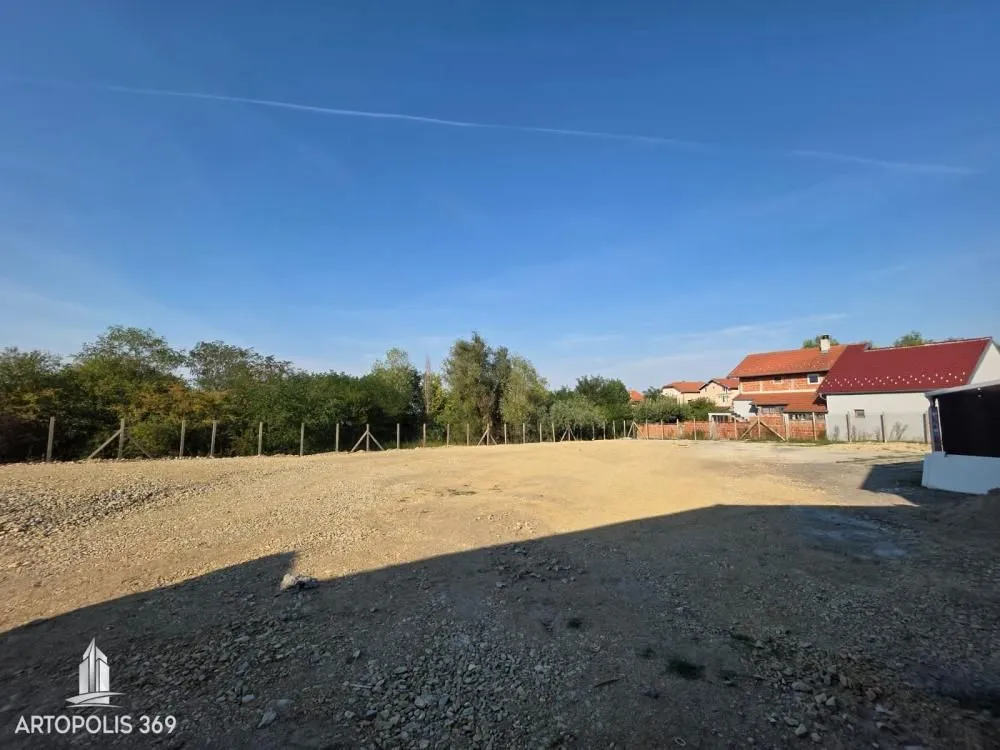 Pogled na ograđeni plac sa zemljanom podlogom i okolnim rastinjem.
