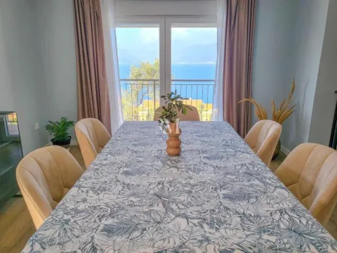 Dining area with a table, chairs, and a sea view through the balcony doors. - image 10