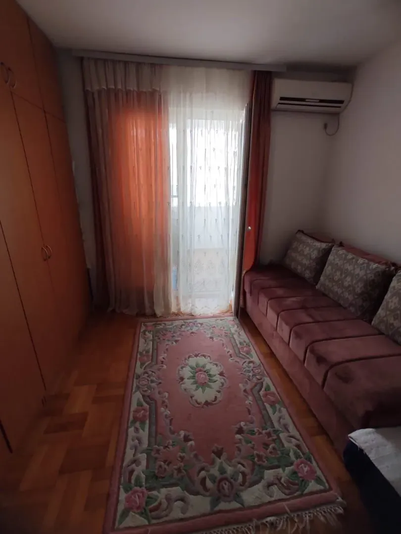 Manja spavaća soba sa kaučem, garderoberom i izlazom na balkon.