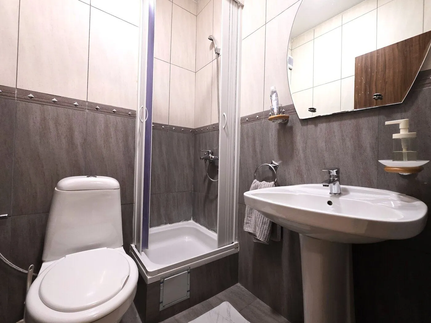 Modernly equipped bathroom with a shower cabin, washbasin, and toilet.
