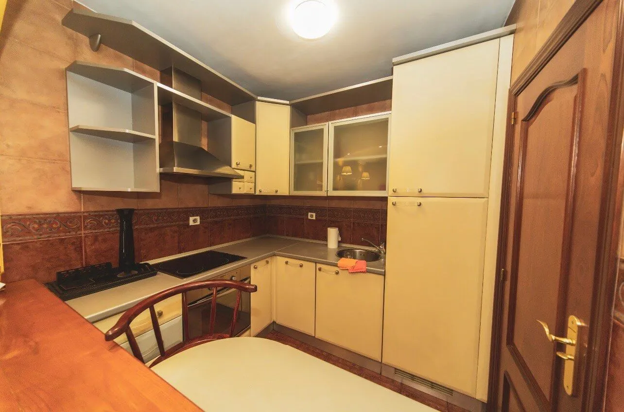 Small kitchen with light cabinetry, a sink, and a built-in cooktop.