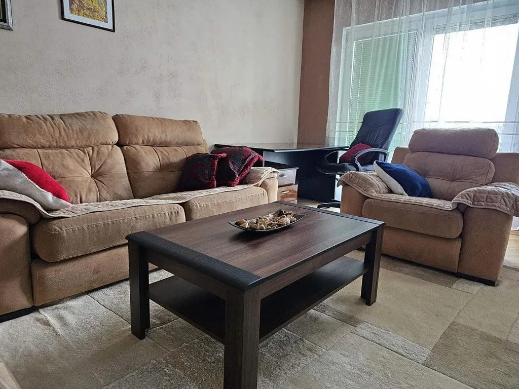 Dnevna soba sa garniturom za sjedenje, stočićem i radnim stolom.
