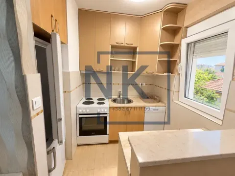 Manja kuhinja sa drvenim elementima, šporetom i frižiderom. - image 3