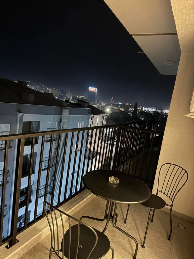 Furnished balcony with seating and a night view of the city.