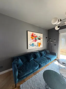 Living room with a comfortable blue sofa, coffee table and artwork on the wall. - image 4