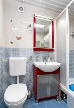 Small bathroom with mosaic tiles, a vanity with a red cabinet, and a shower enclosure. - image 7