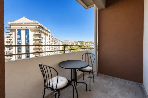 Covered balcony with seating set and view of surrounding buildings and hills. - image 7