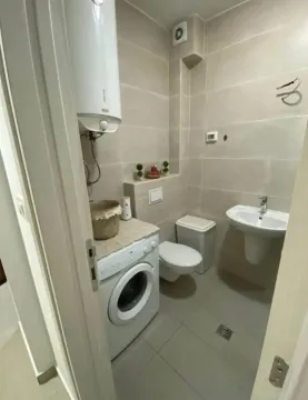 Small bathroom with a washing machine, water heater, and sanitary fixtures. - image 7