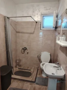 Smaller bathroom with a shower cabin, sink and toilet, tiled in beige ceramic tiles. - image 6