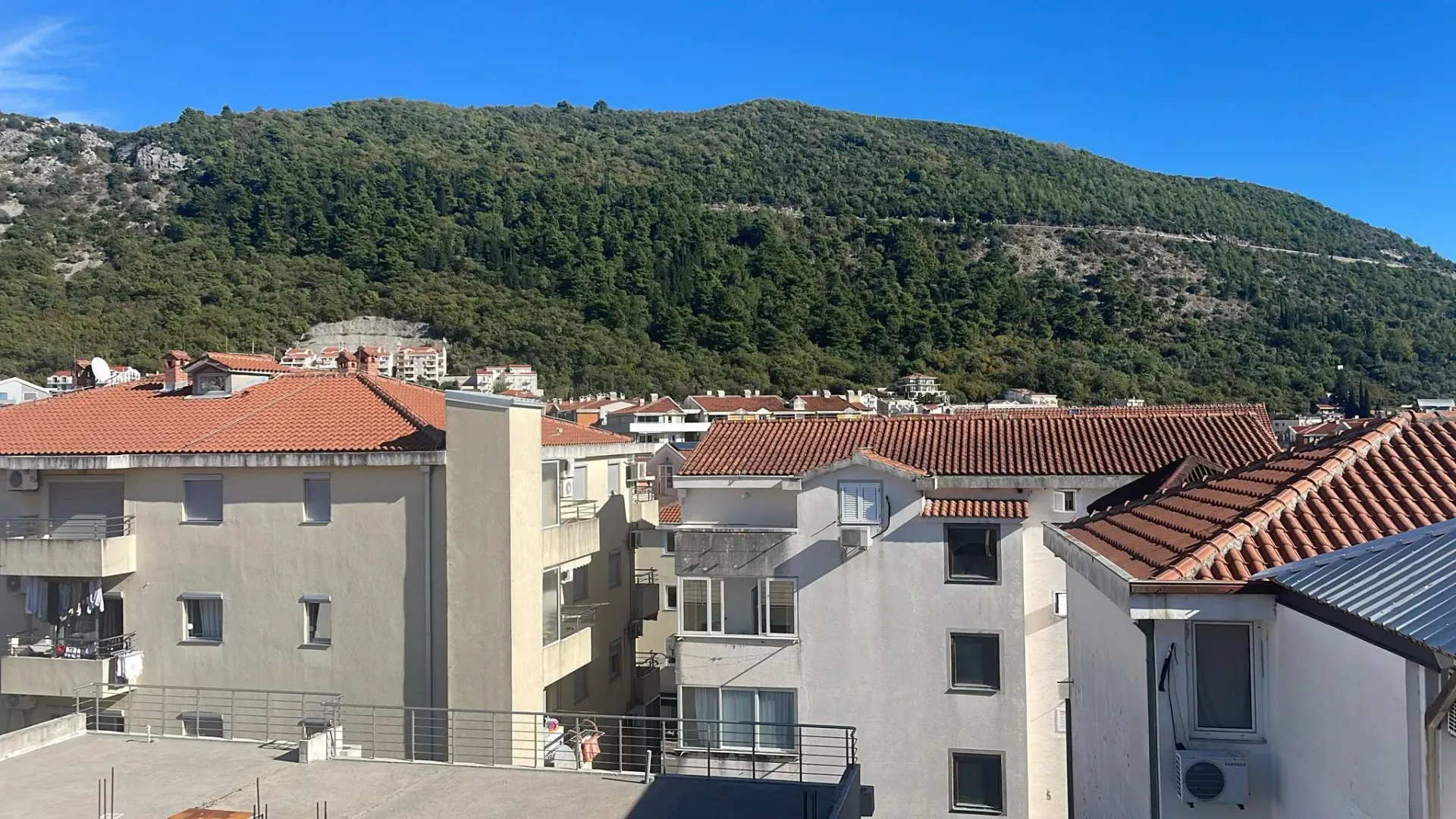 Pogled sa terase na okolne zgrade i brdo obraslo šumom.