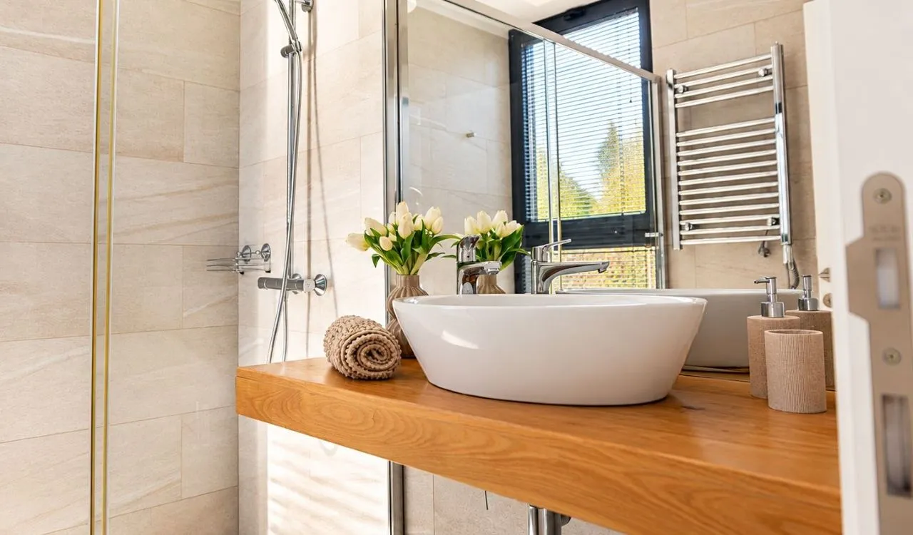 Modern bathroom with a washbasin on a wooden countertop and a shower cabin.
