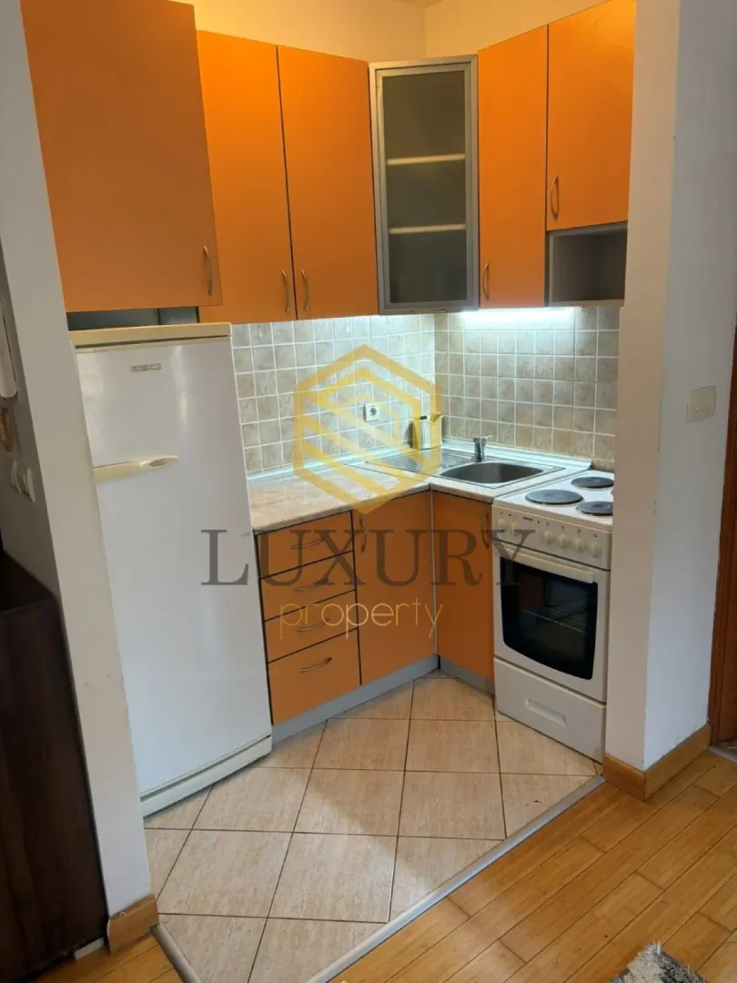 Small kitchen with orange cabinets, refrigerator, and stove.
