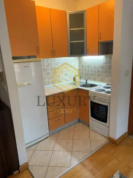 Small kitchen with orange cabinets, refrigerator, and stove. - image 3