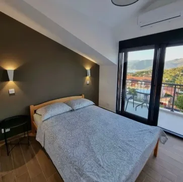 Furnished bedroom with a double bed and access to a balcony with a view. - image 4
