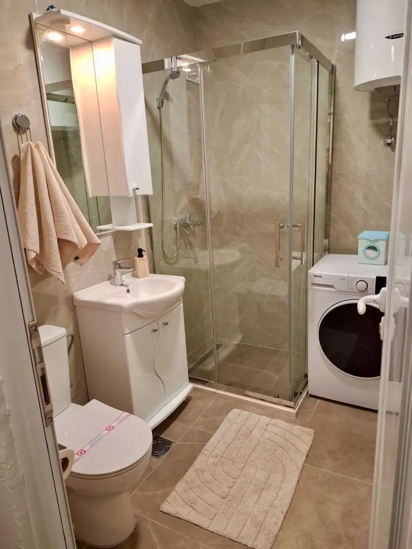 Compactly equipped bathroom with a shower cabin, sink, and washing machine.