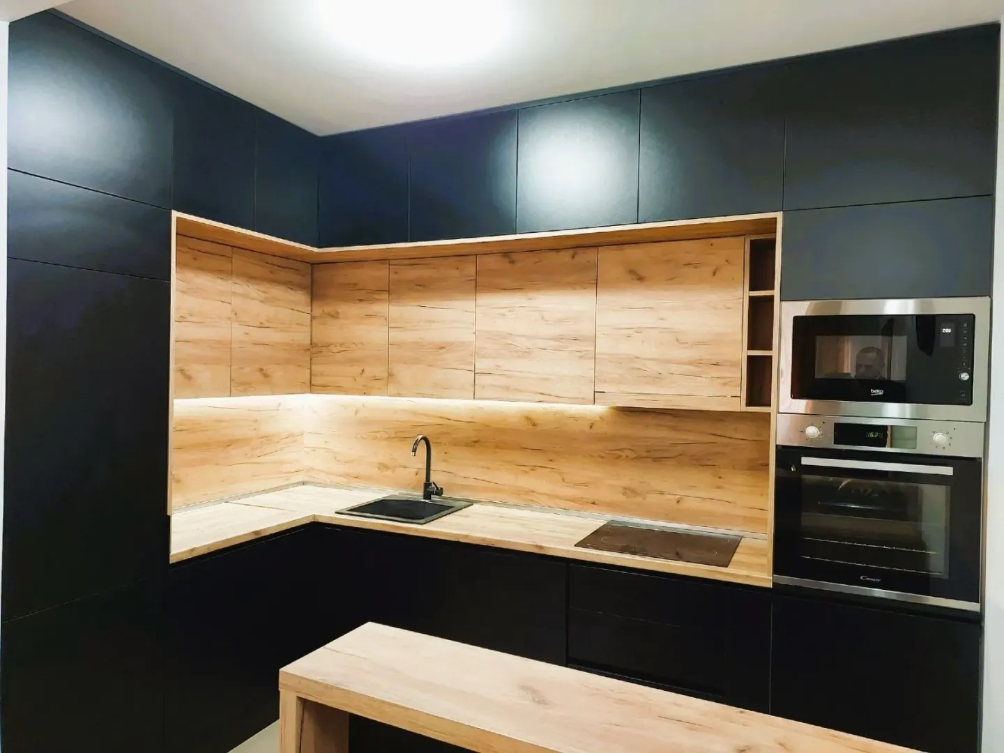 Modern kitchen with black cabinetry and wood-tone details.