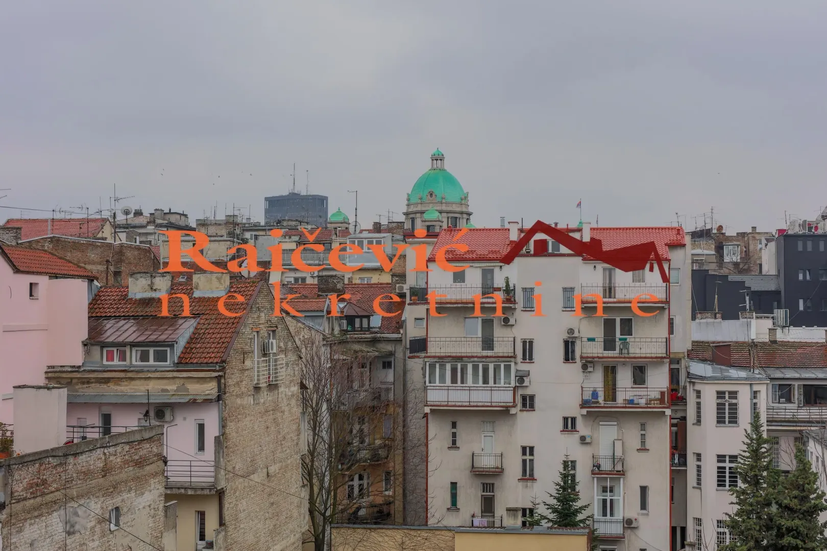 Pogled sa prozora na gradske krovove i zgrade.