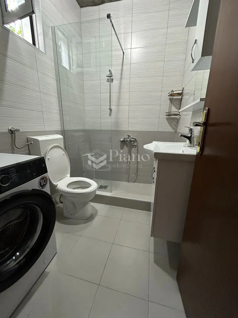 Smaller bathroom with a shower cabin, washbasin and washing machine.