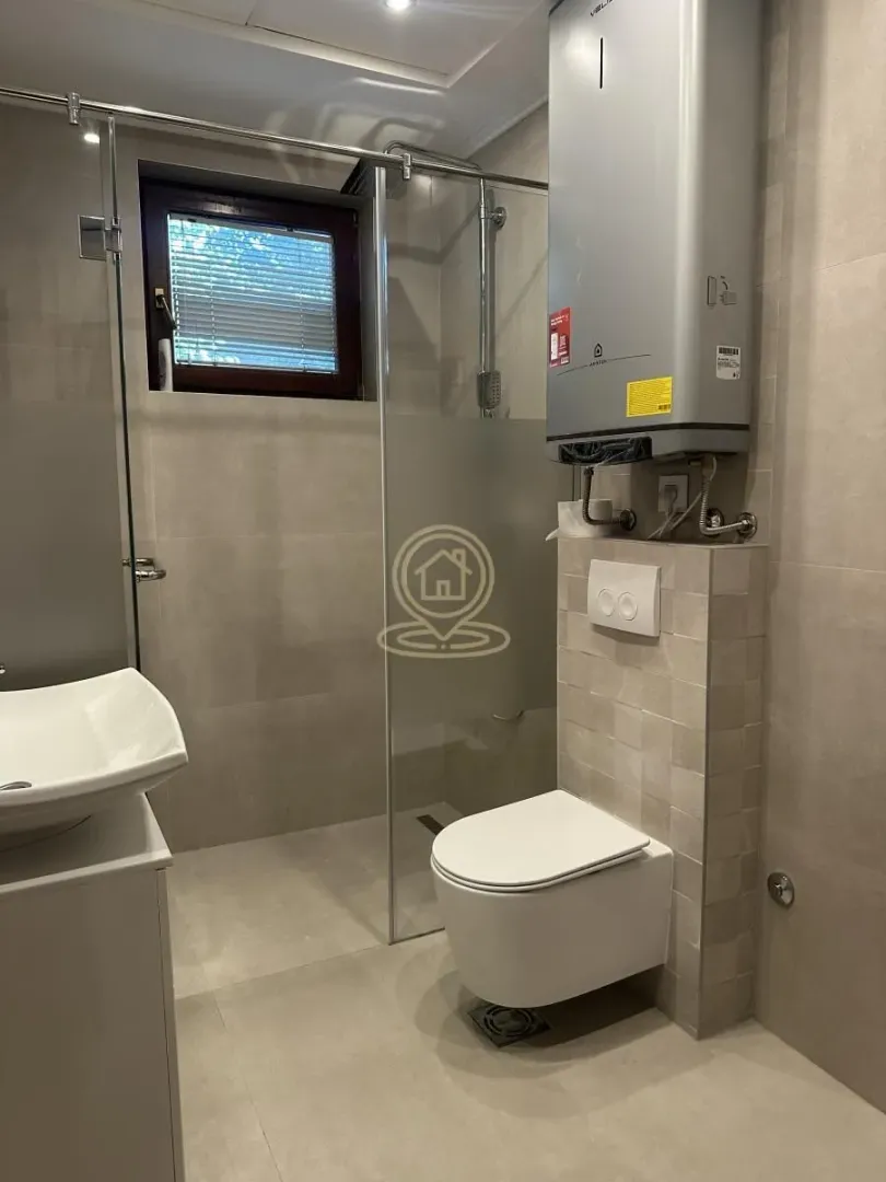 Modern bathroom equipped with a walk-in shower, wall-hung toilet, and water heater.