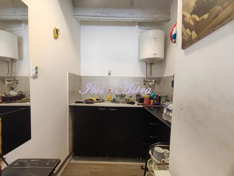 Small kitchen with a sink, cabinets, and a water heater.