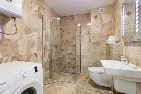 Kupatilo obloženo keramičkim pločicama sa tuš kabinom, umivaonikom, toaletom i veš mašinom. - image 7