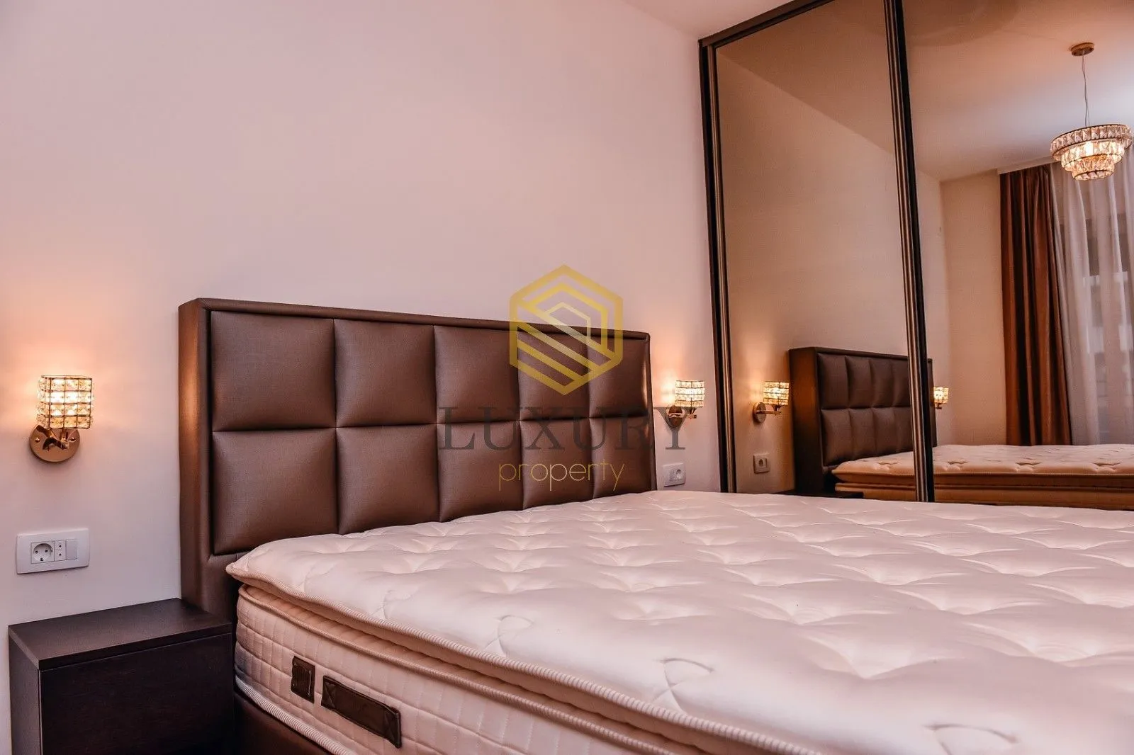 Furnished bedroom with a double bed and a mirrored built-in wardrobe.