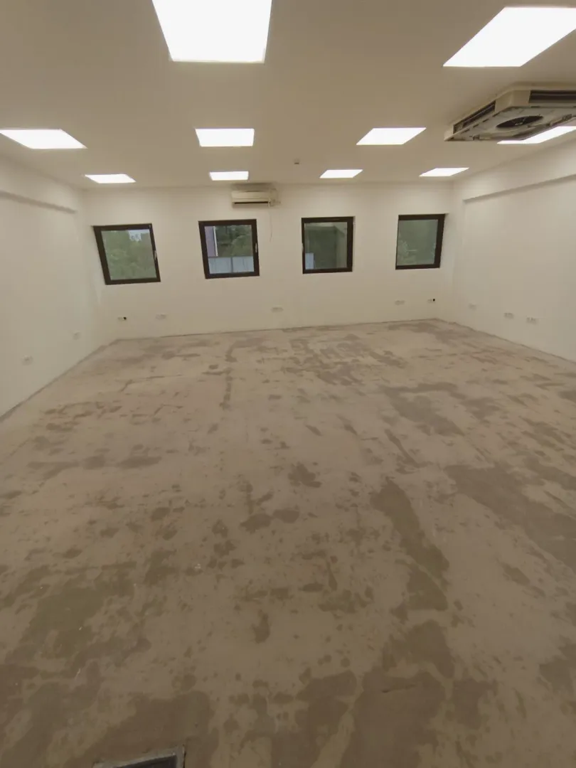 Spacious empty room in shell condition with windows and lighting.