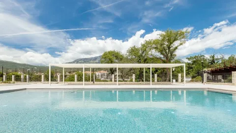 Veliki vanjski bazen sa popločanim dijelom i natkrivenom strukturalnom pergola konstrukcijom u pozadini. - image 15
