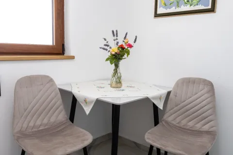 Small dining table with two chairs and a vase of flowers. - image 7