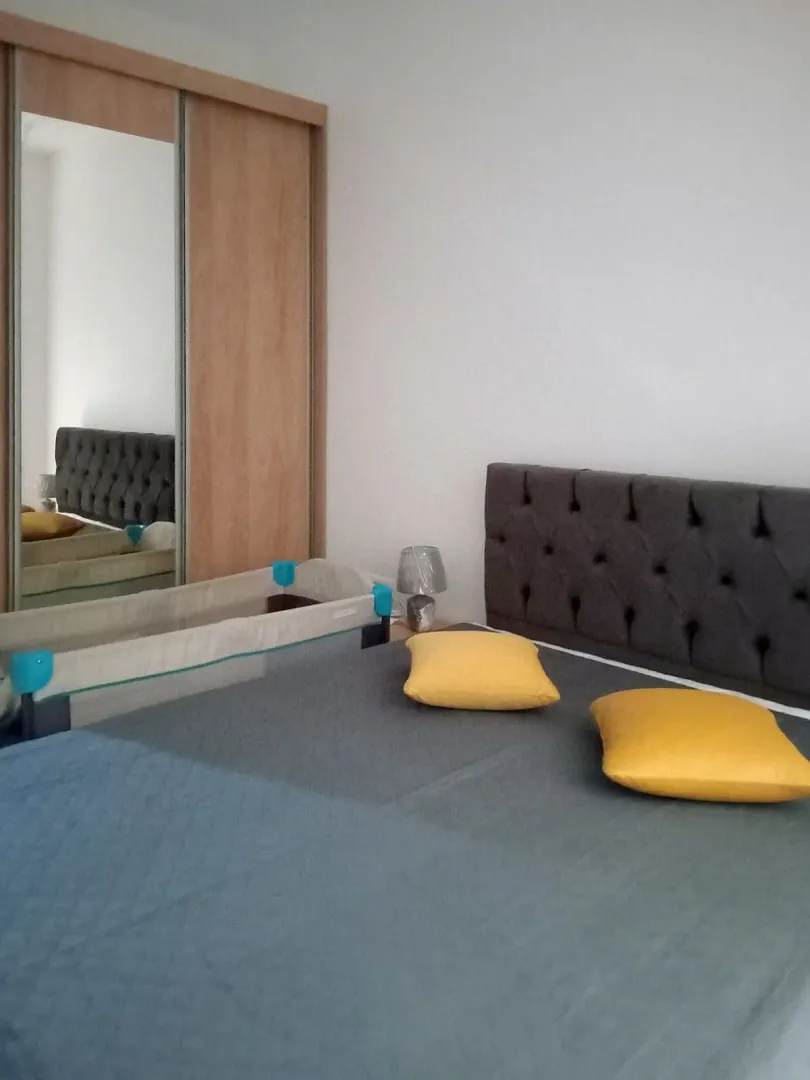 Bedroom with a double bed, a baby crib, and a mirrored built-in wardrobe.