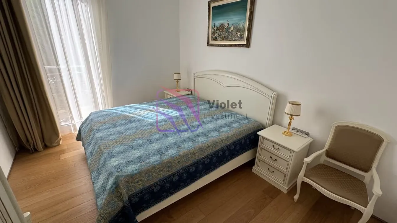 Spavaća soba sa bračnim krevetom, noćnim stočićima i foteljom.